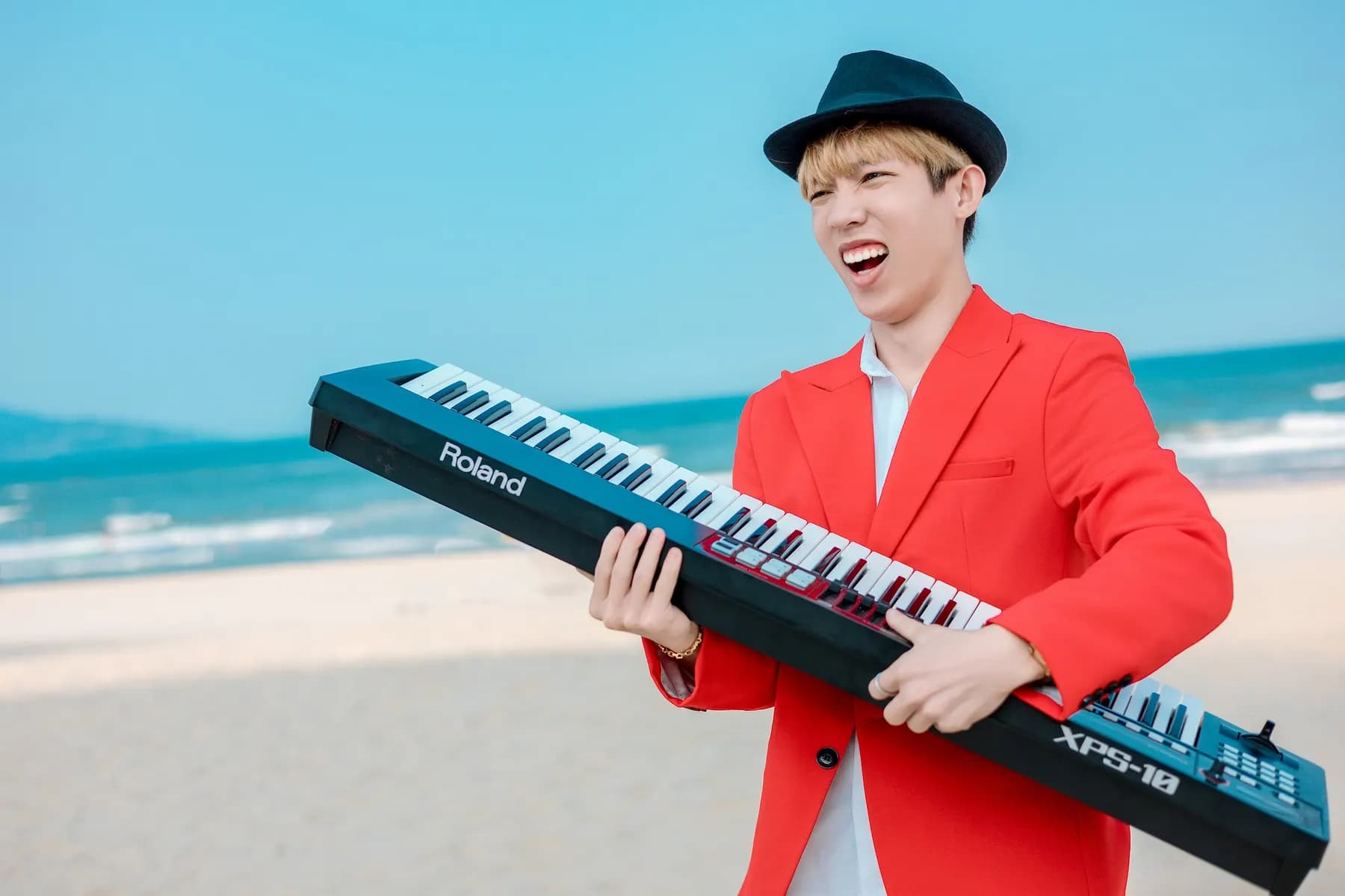Keyboardist in a red blazer playing on the beach