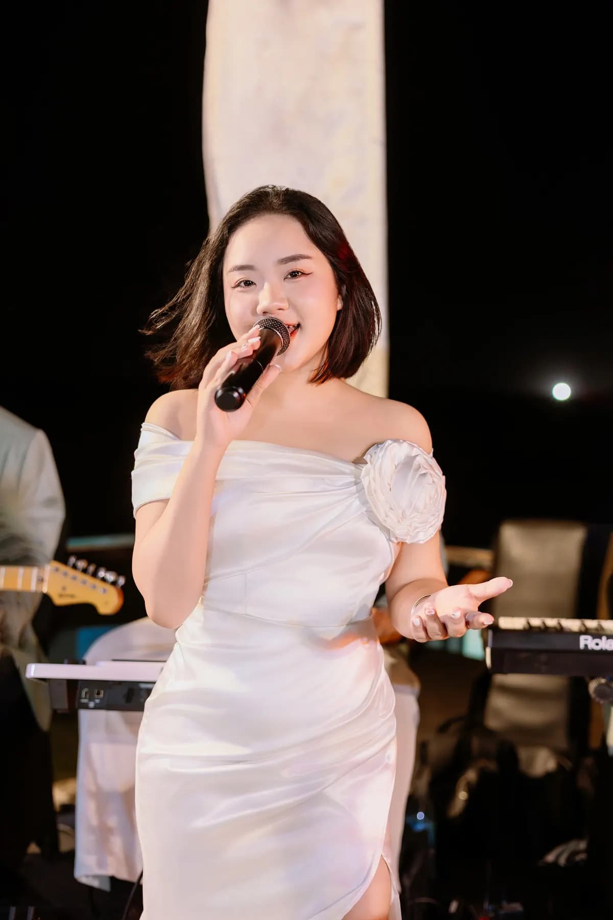 Singer in a white dress performing at night