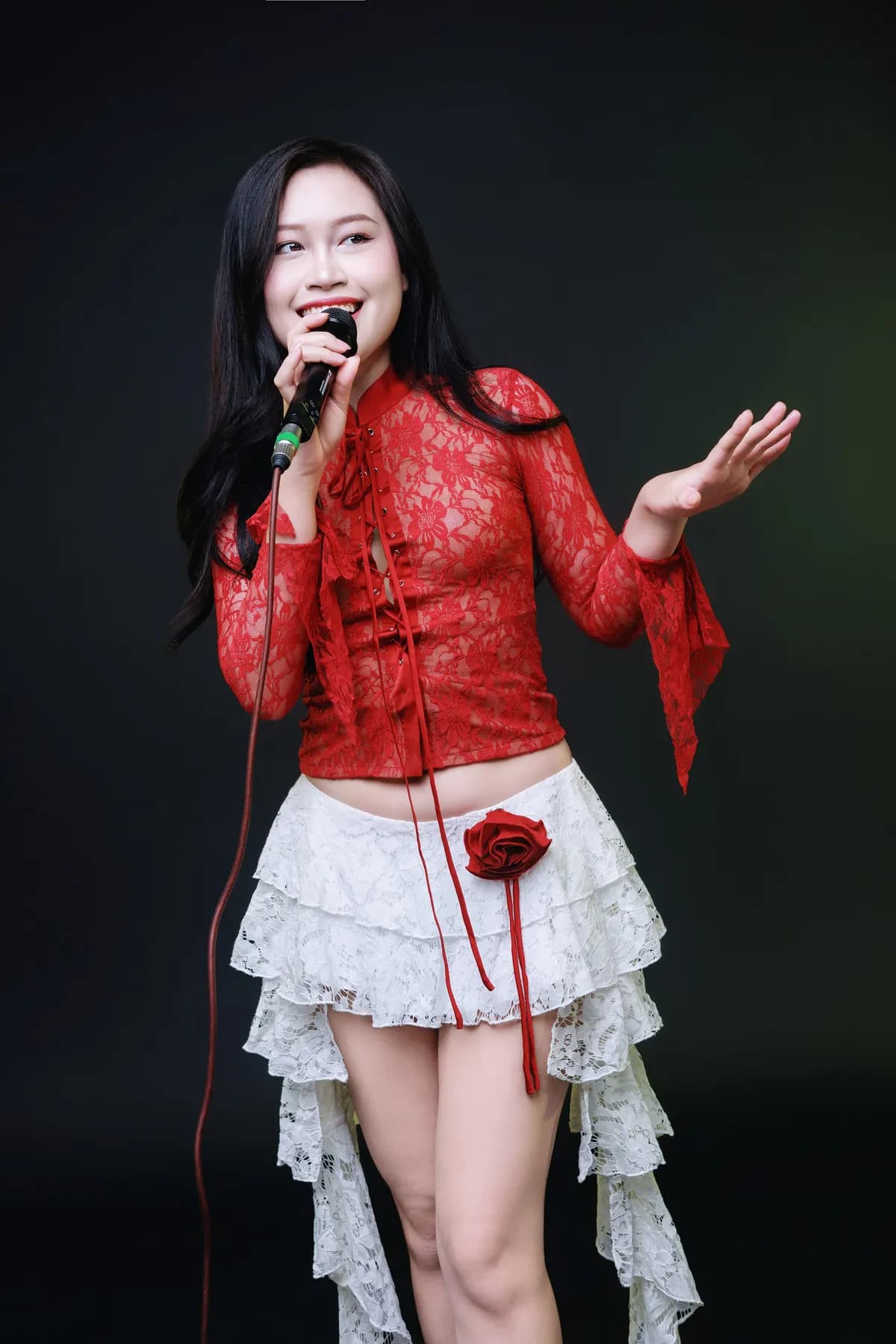 Singer in a red lace top holding a microphone