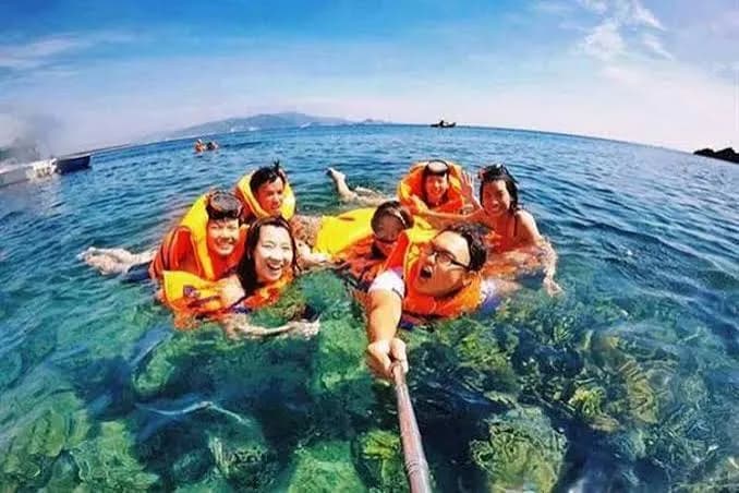 Friends in life jackets taking a selfie in clear blue water