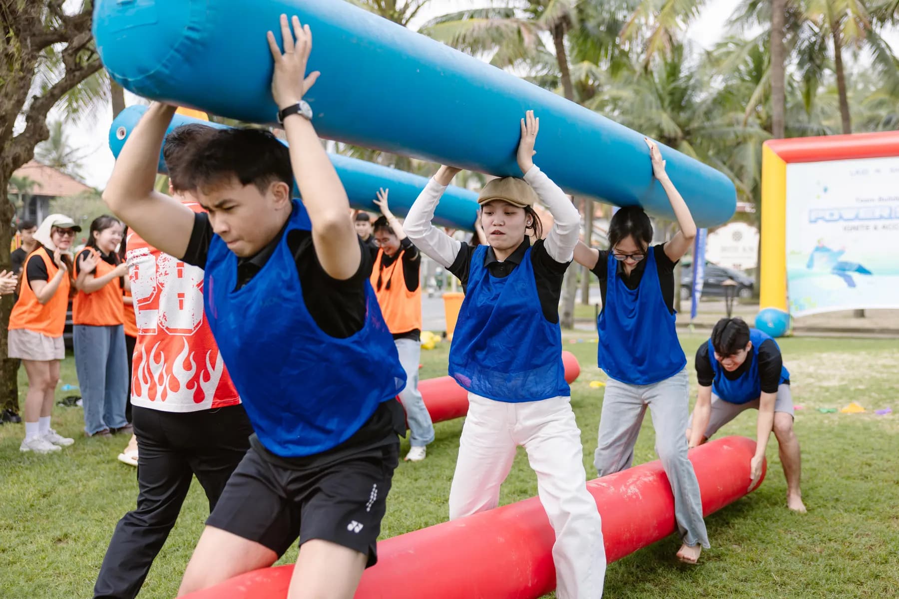 Blue team carrying an inflatable log overhead while stepping over another