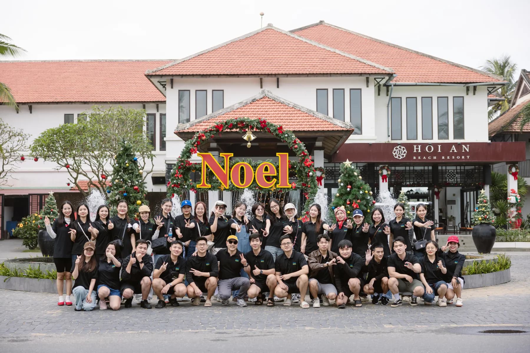 Whole team in black T-shirts posing in front of the resort entrance