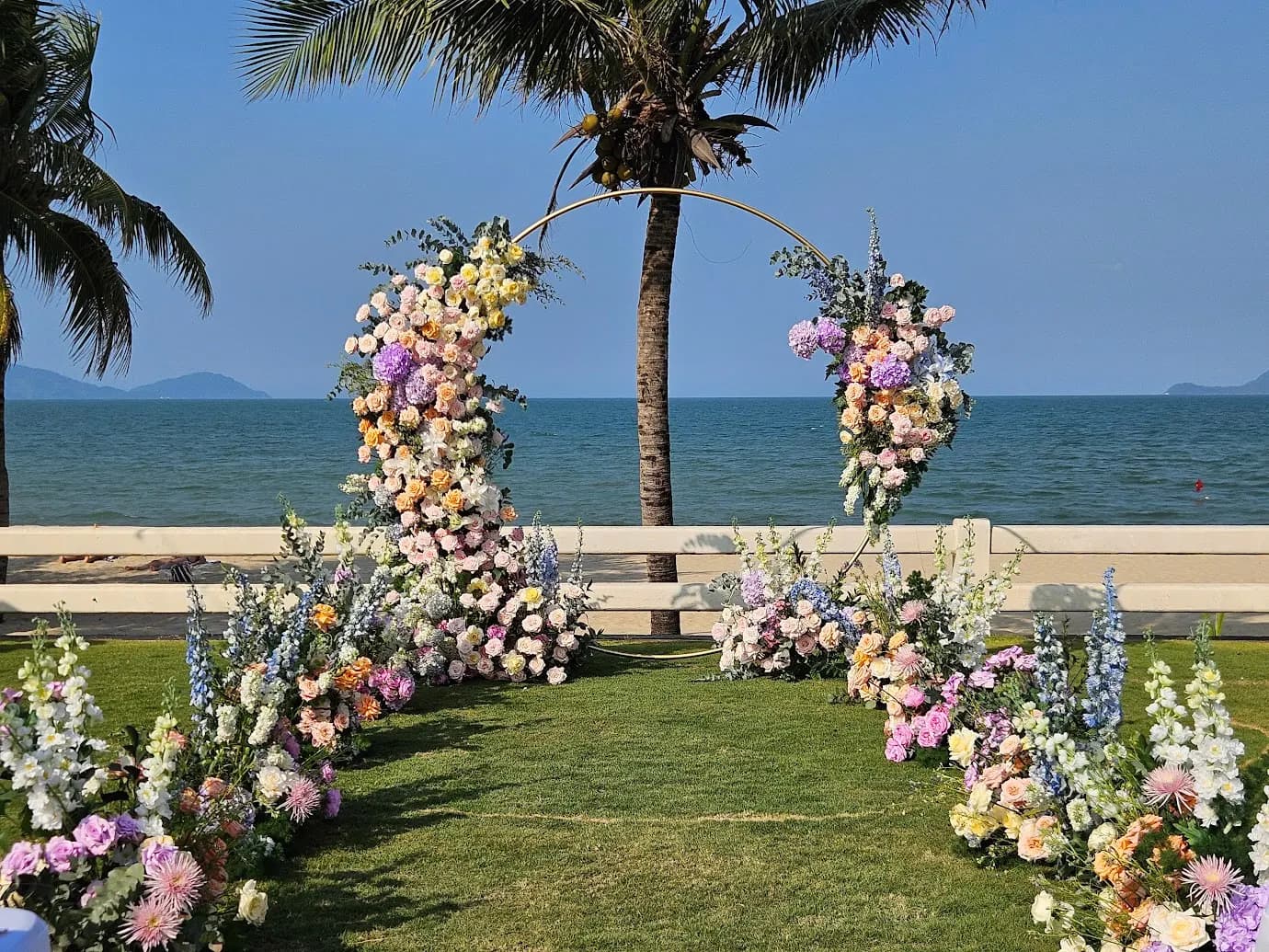 Pastel floral arch on a lawn by the sea