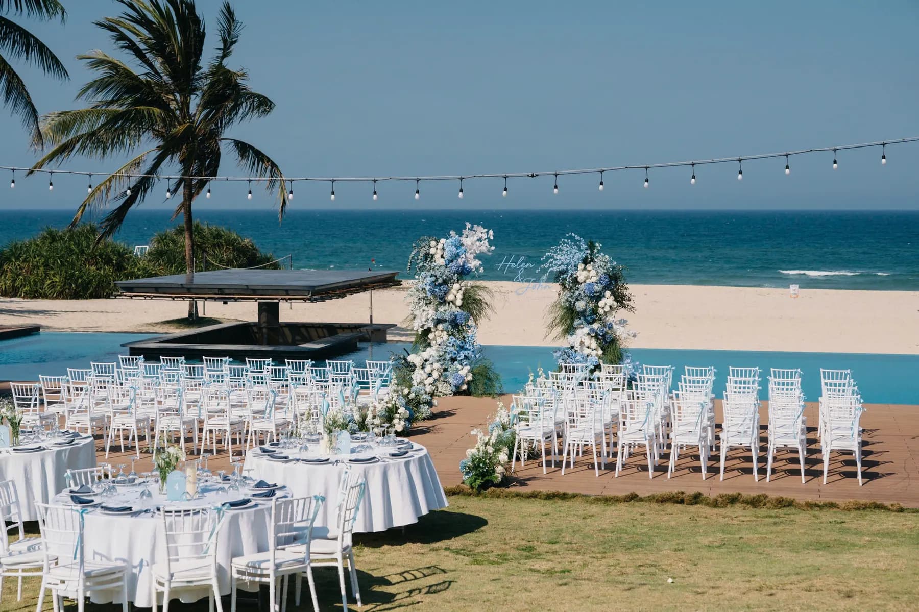 Wedding tables and ceremony chairs set between a pool and the beach